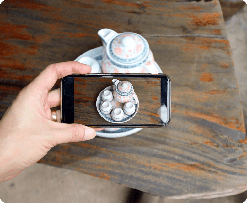 A person taking a photo of a tea pot