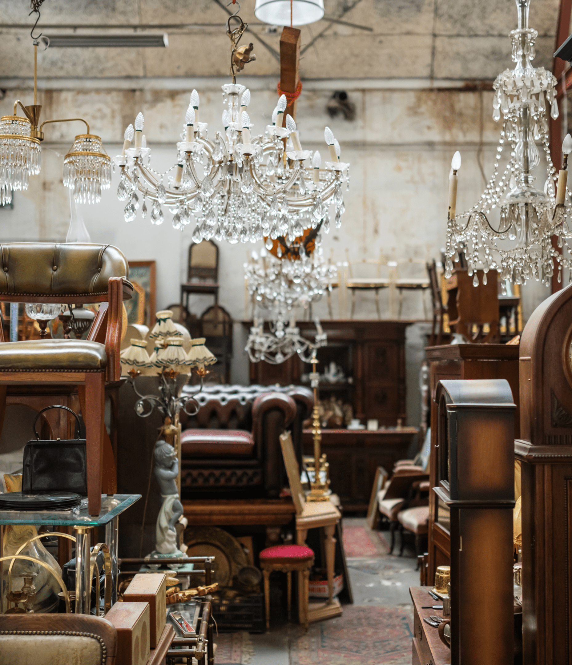 An antique store with chandeliers, wooden furniture, and various vintage items crowded together in a large, well-lit space.